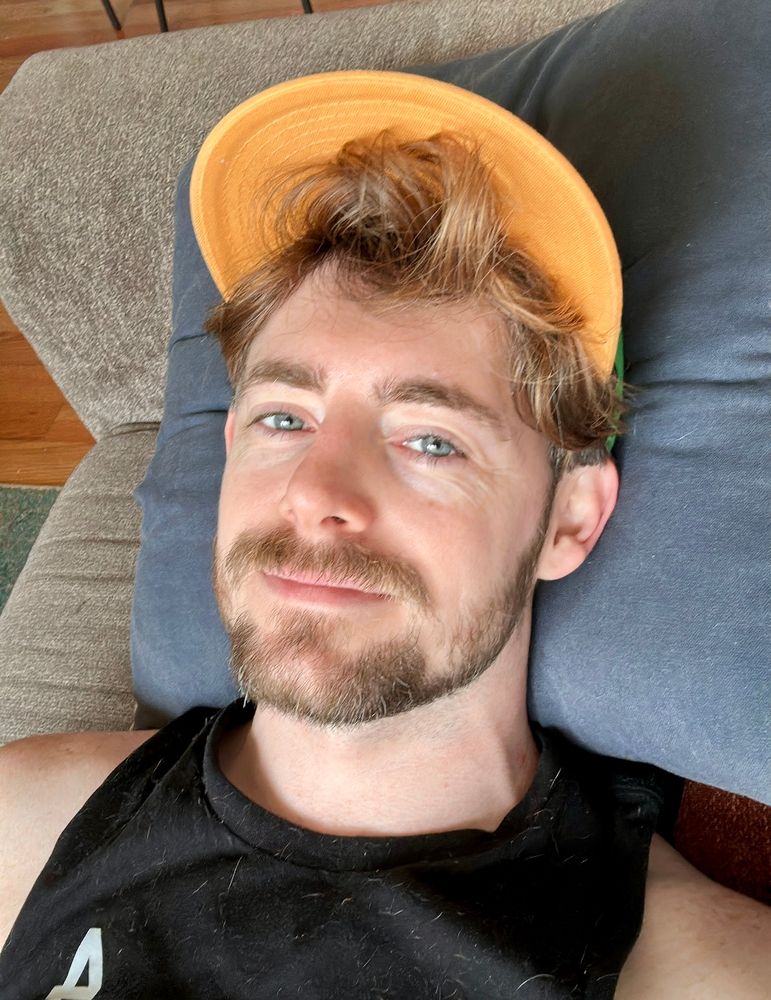 Selfie on couch with yellow-brim hat and black shirt
