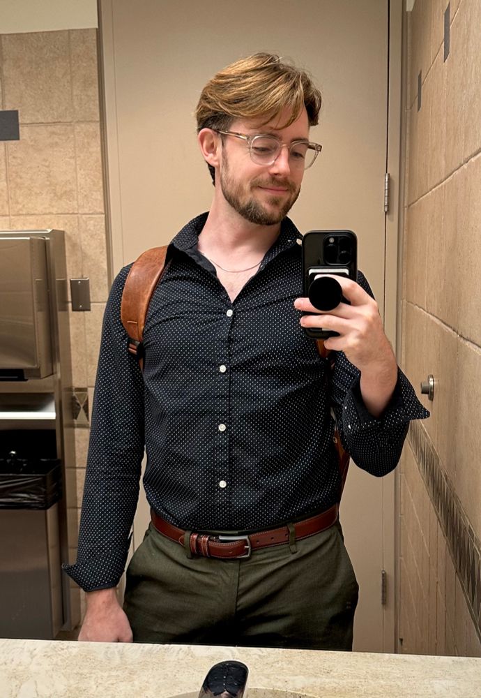 mirror selfie with navy polka dot shirt and earth green pants