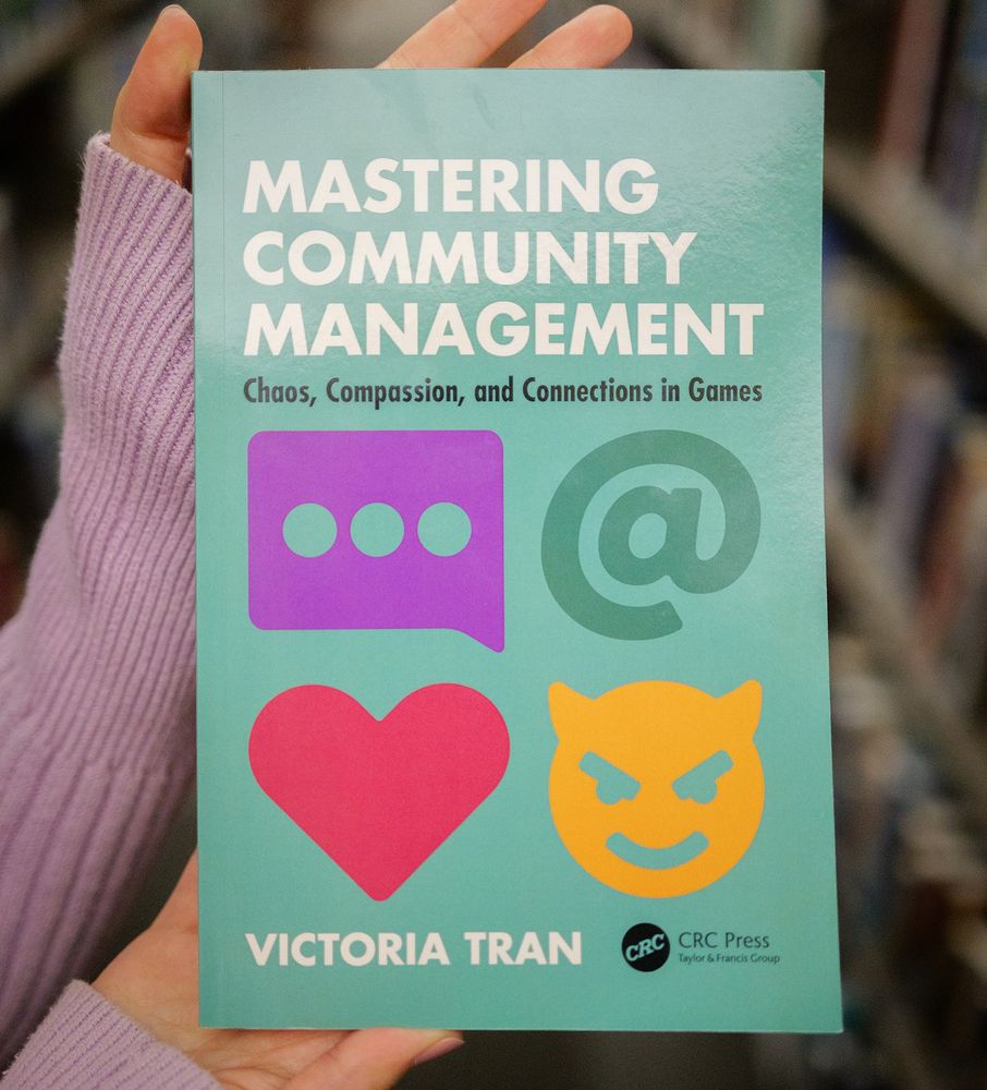 Holding up my book "Mastering Community Management: Chaos, Compassion, and Connection in Games".