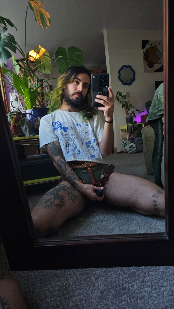 Same scene as before, but this time, Cosmo appears to be more stoic. They are gripping their dildo as if taking a dick pic.