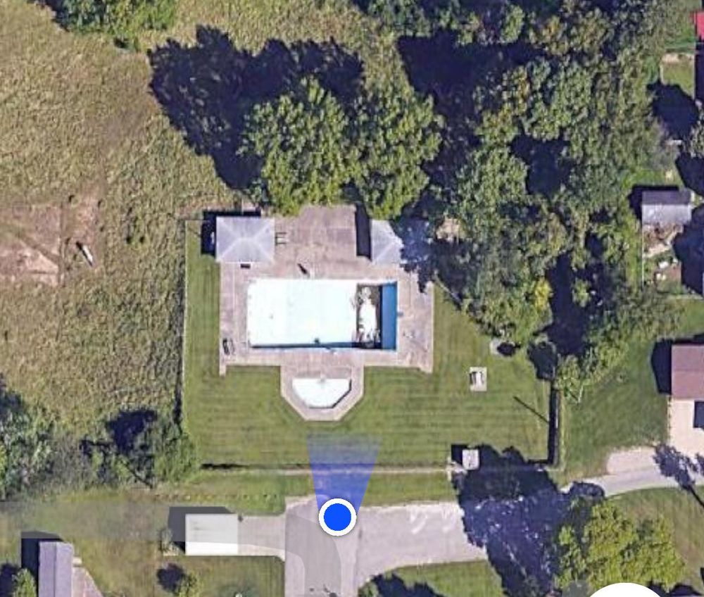 An ariel view of a pool, with a blue dot indicating the viewers location, directly in front of the now nonexistent neighborhood pool.  