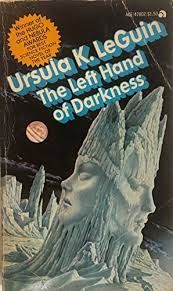 Cover of Ursula K. Le Guin's The Left Hand of Darkness. An ice sculpture containing a stereotypically feminine and stereotypically masculine face, staring in opposite directions like the head of Janus. Background is more icy, spiky terrain, and behind it a black sky with wispy clouds and an unknown planet.