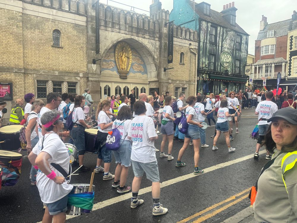 Bruhlio samba band leading the march at Brighton Trans Pride.  They are all wearing “Trans Roghts are Human Rights” t-shirts