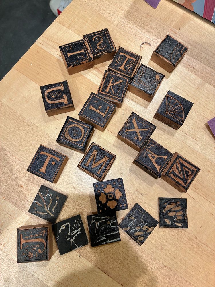22 inked woodblocks carrying various letters from the alphabet and other images.