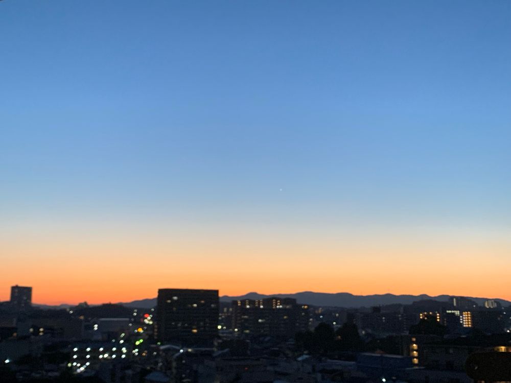 夜空に朝の日が差し始め、空に青みが増し、
下から順にオレンジ色から青に変わるようなグラデーションで色付けされている風景写真