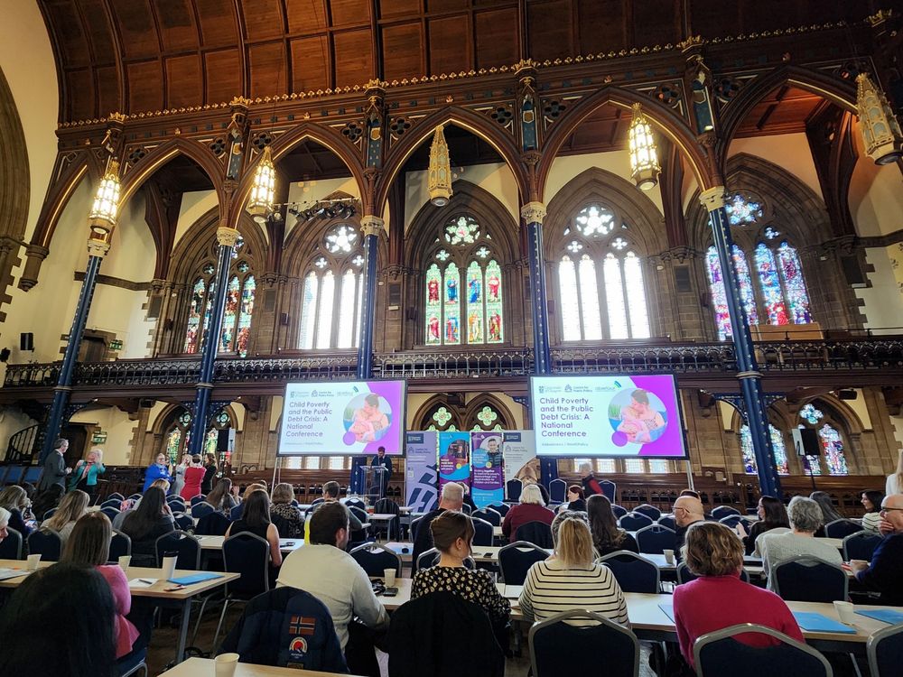 Room full of people sitting awaiting the beginning of conference.