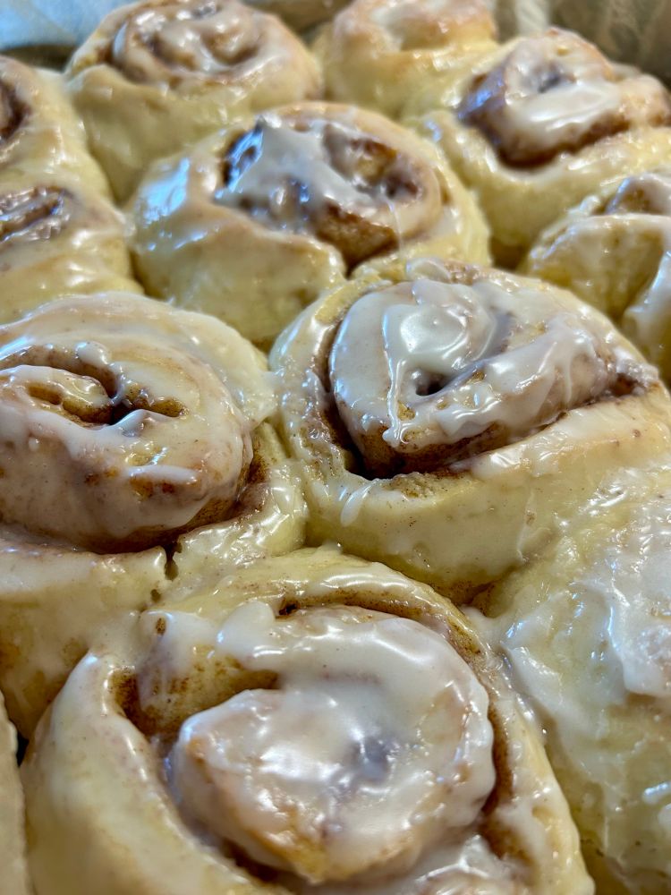 Nahaufnahme von gebackenen und mit Zuckerguss bestrichenen Zimtschnecken. 
