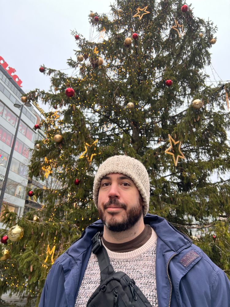 My partner standing in front of a giant Christmas tree 