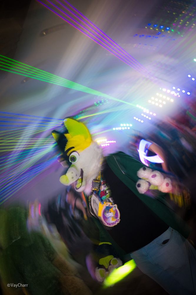 myself in my fursuit wearing a green hoodie over a black t-shirt with the CFz 2022 design and light blue jeans on the dance floor at CFz. there are lots of various bright and/or colourful lights in the background and the image has circular motion blur

also the caption is a messed up version of “how it feels to chew 5 gum”, a very old advert for chewing gum which became a meme idk i felt the need to explain it