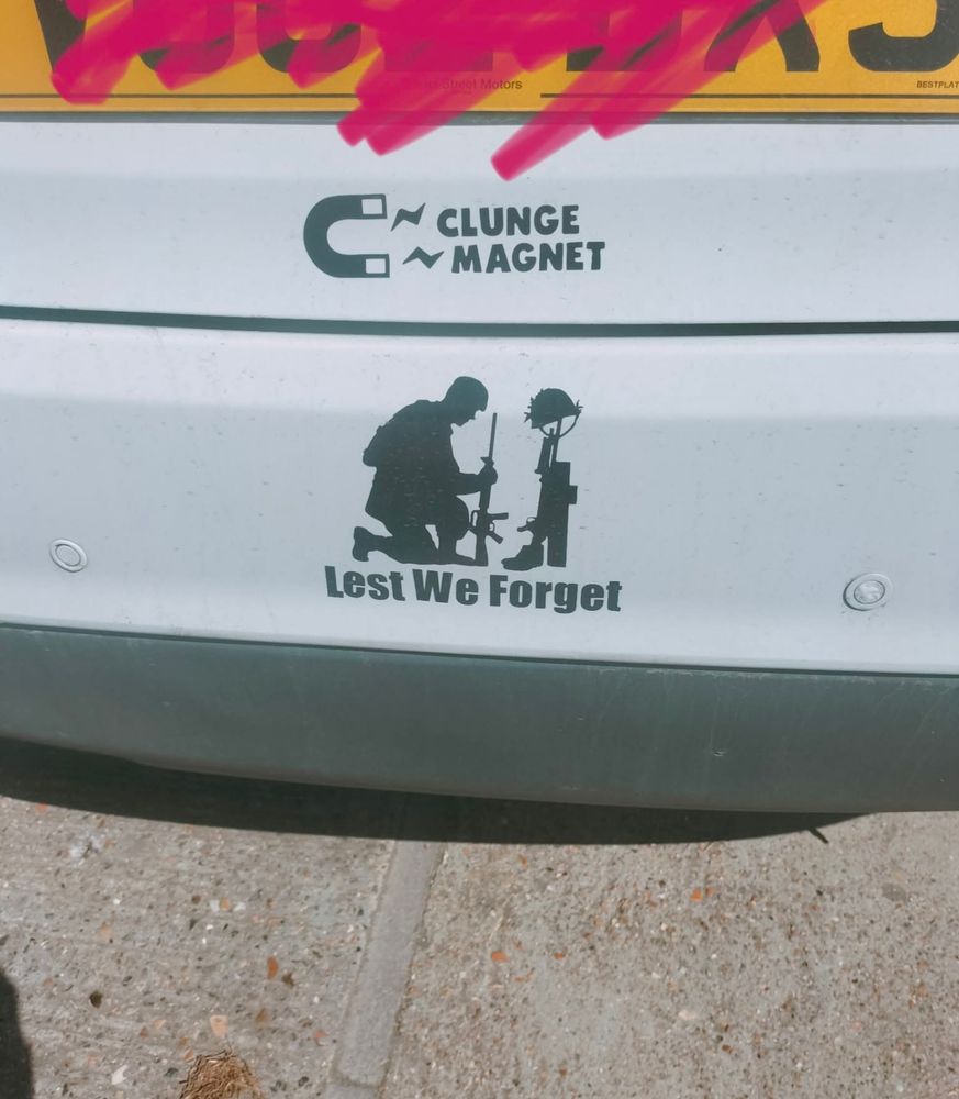 Rear bumper of a white car with two bumper stickers. One is a horseshoe magnet with 'CLUNGE MAGNET' written underneath. 

Below that is a silhouette of a kneeling soldier in front of a memorial, with the words 'Lest We Forget'