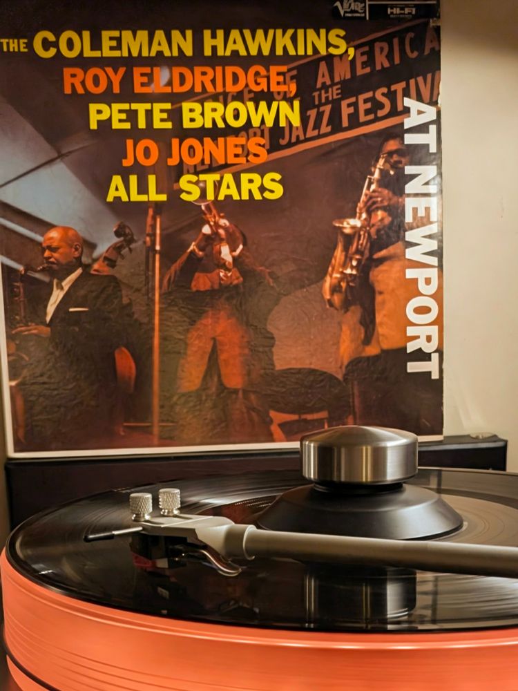 At Newport by Coleman Hawkins, Roy Eldridge, Pete Brown & Jo Jones All-Stars, vinyl LP playing on VPI Scoutmaster turntable, 12-pound acrylic platter glowing orange. Audio Technica AT-VM95ML cartridge.

Cover is a photo of the musicians live on stage at the 1957 Newport Jazz Festival, though only the trumpet and sax players are fully visible

#vinylsky #vinyl 