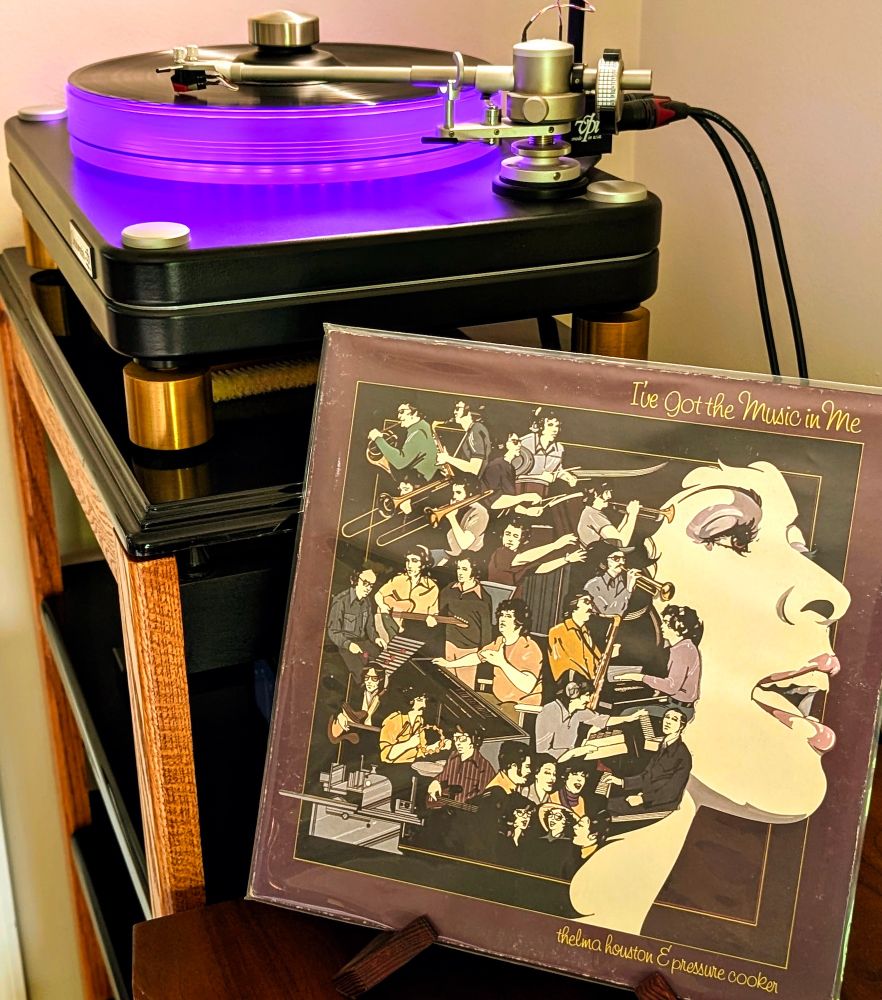 Thelma Houston & Pressure Cooker – I've Got the Music in Me (Sheffield Lab, 1975) playing on VPI Scoutmaster turntable, 12-pound acrylic platter glowing violet. Audio Technica AT-VM95ML cartridge.
Album cover (front, right) is a Nagel illustration showing Thelma Houston (right, facing right) singing in profile, with smaller montages of the musicians filling the left side, a deep red-violet is the main color tone

PSA: This is a remarkable, standout, reference recording. 

Each side was recorded live to master disc in single take, no processing or overdubs. I'm guessing the mix of funky, jazzy, poppy covers is not what most people are looking for in a demo disc? But it's worth picking up. The releases I have (Dad had 2) are super cheap.

Not pictured:
NAD M10v3 streaming integrated amplifier
JBL Paragon wired with Anticables

Selection from Dad's Collection
#nowplaying #nowspinning #vinyl #sheffieldlab #audiophile
