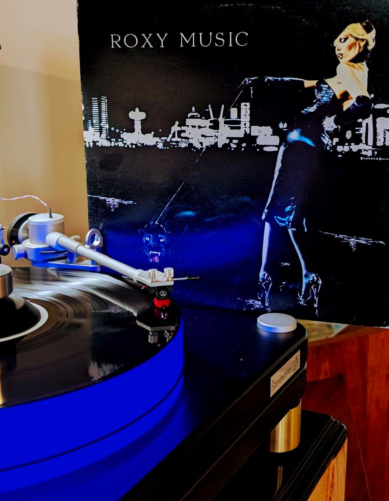 Roxy Music For Your Pleasure vinyl Playing on VPI Scoutmaster turntable, 12-pound acrylic platter glowing blue. Audio Technica AT-VM95ML cartridge.

Album cover (top, right) is an illustration or illustration over photograph of a nighttime scene: a blonde woman in a black vinyl dress and stiletto heels walks a black panther on a leash in front of a white-lit skyline
