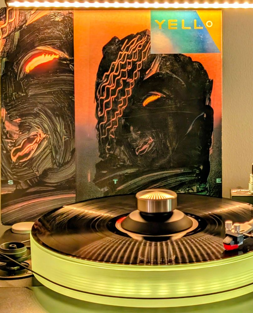 Yello 'Stella' vinyl playing on VPI Scoutmaster turntable, platter glowing yellow

Cover is a painting of a face in black paint on glass, and you can see the setting sun glowing through the eye.