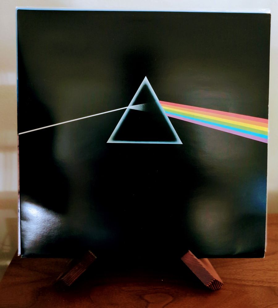 Pink Floyd's Dark Side of the Moon album cover, a solid black background with an illustration "inspired by a photograph of a prism with a beam of white light projected through it and emerging in the colours of the visible spectrum" found in a textbook