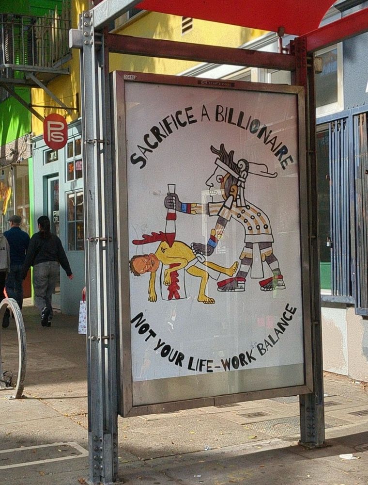 A bus stop in San Francisco depicting an Aztec stabbing Elon Musk in the heart. Text: SACRIFICE A BILLIONAIRE NOT YOUR LIFE-WORK BALANCE 