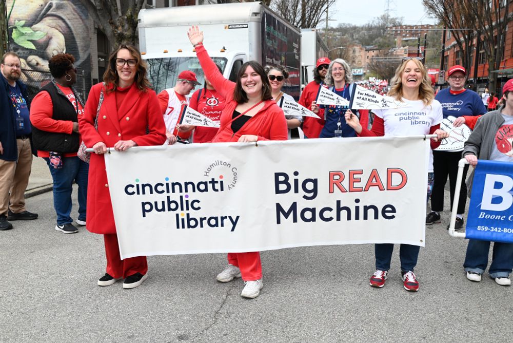 Library staff holding a Big Read Machine sign at the Reds Opening Day Parade.