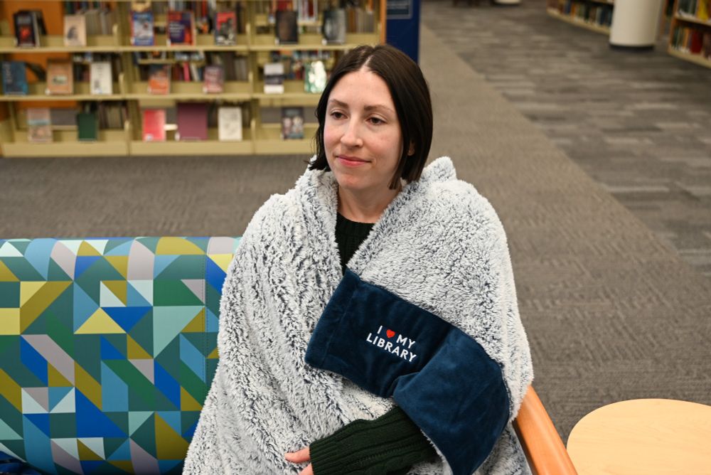 Staff member wearing an I love my library blanket.