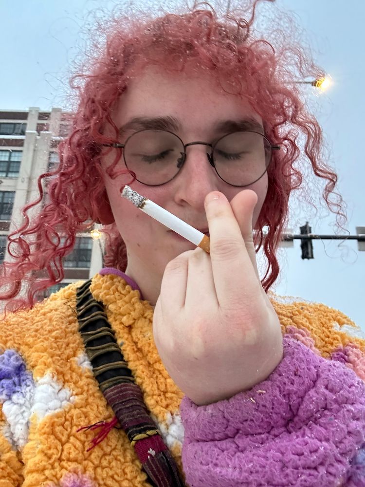 me in a jacket w a sweaty face and my hair in a pony doing heart fingers w a cig also in hand