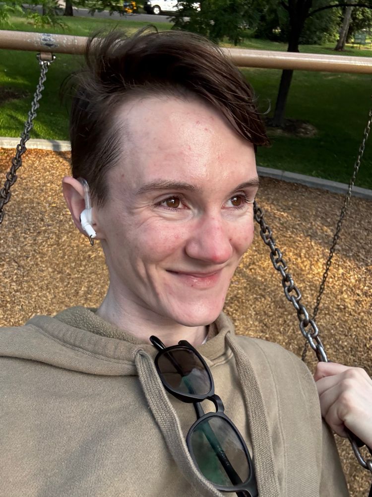 selfie of a white person smiling on a swing