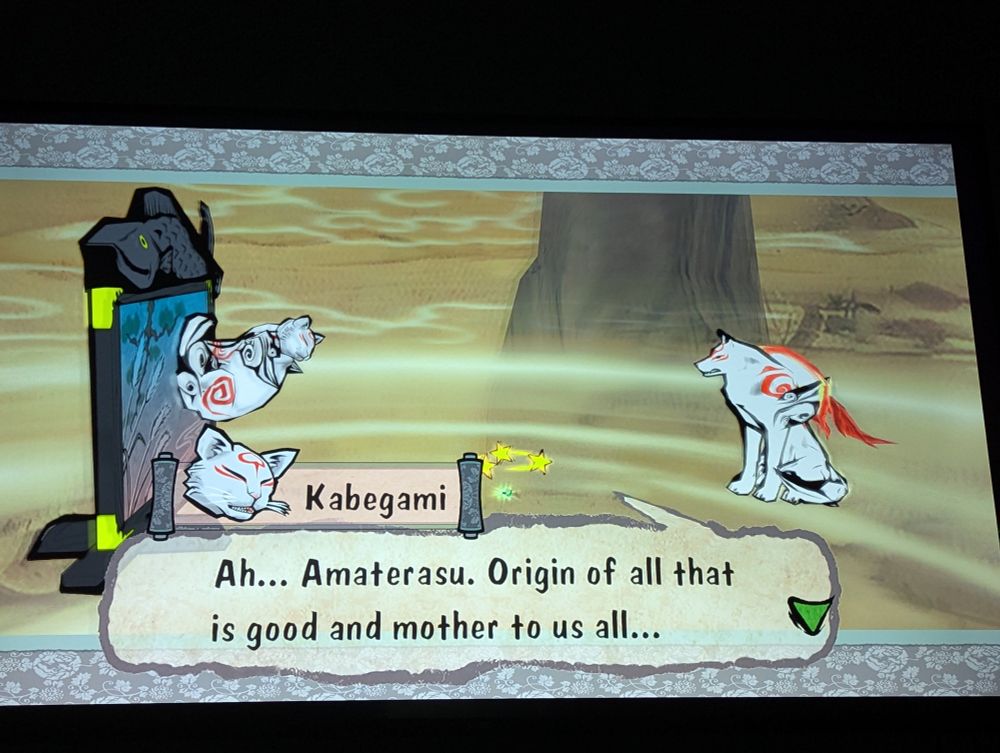 Kabegami the cat from Okami saying "Ah... Amaterasu. Origin of all that is good and mother to us all..."
Issun the tiny artist is in the middle with stars above his head, and Amaterasu is across from Kabegami. They are in the astral realm, a yellow swirly area above the clouds with giant mountain tops in the distance.