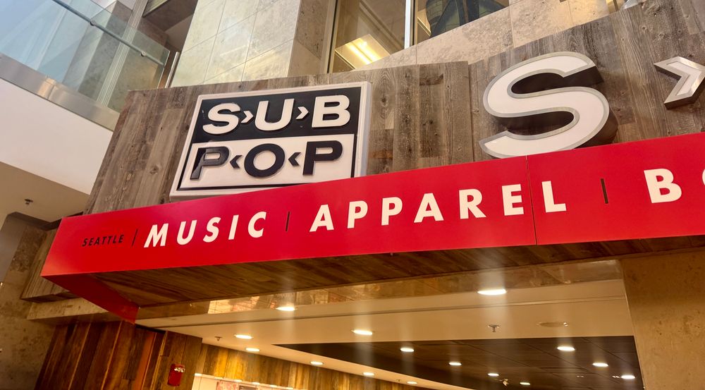 Red Sign for Sub pop records merch store in Seattle-Tacoma International Airport with black and white SP logo 
