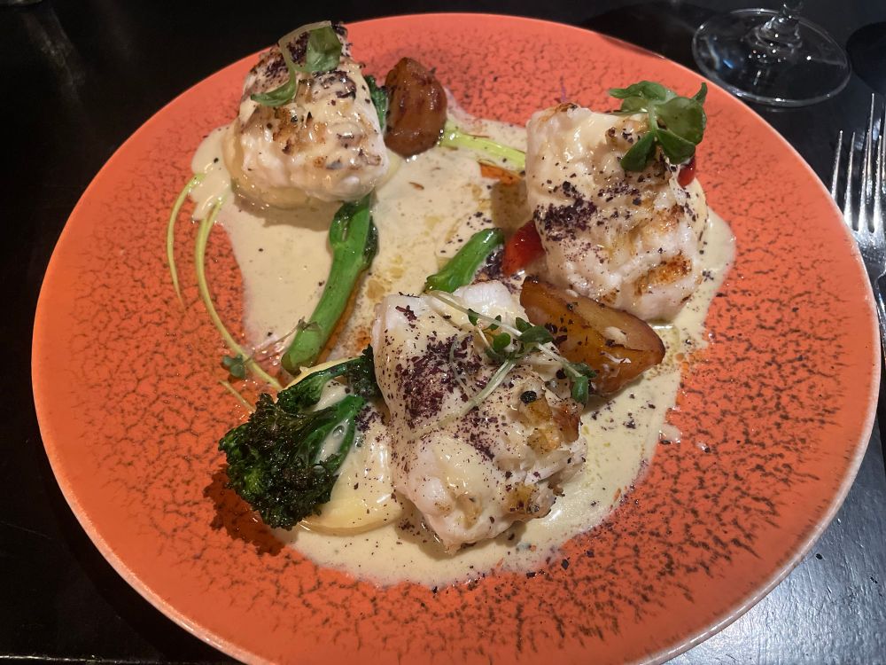 Cooked ling fish, served with a sauce, mashed potatoes, and vegetables.