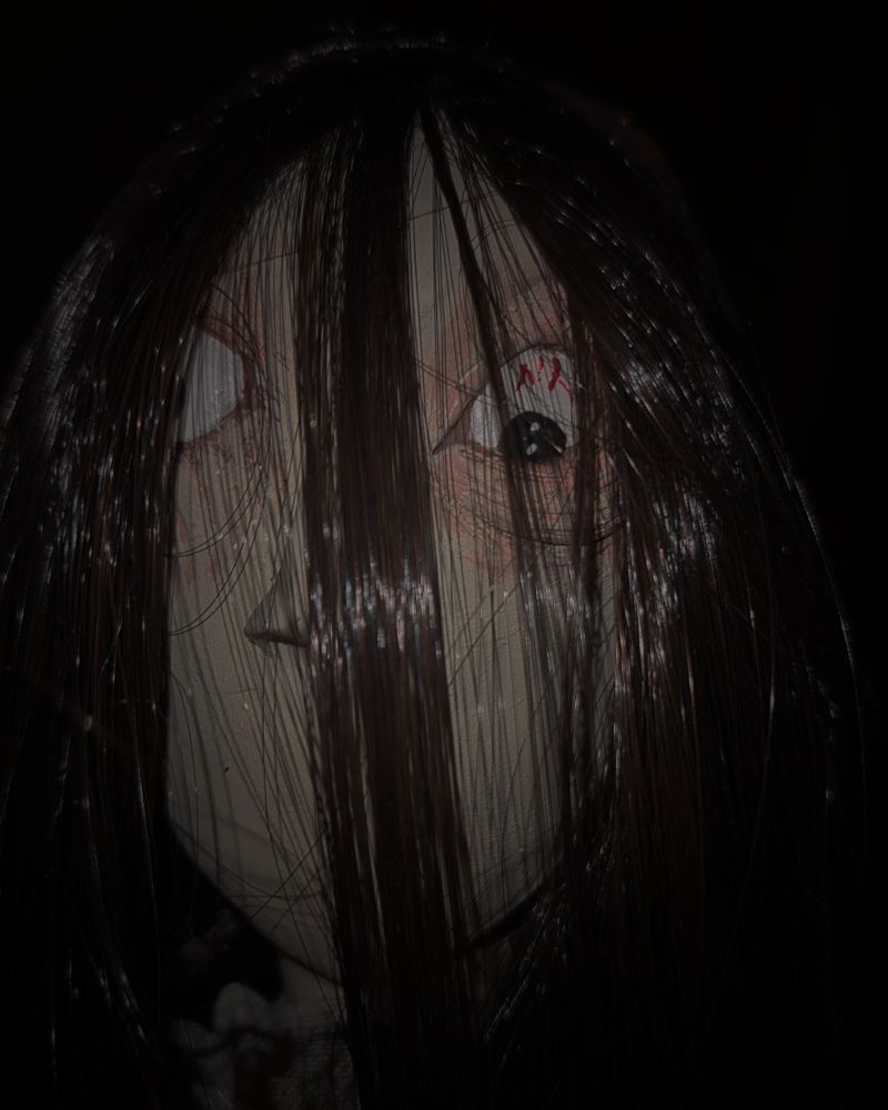 Dark photo of a doll face close up with a creepy eye.