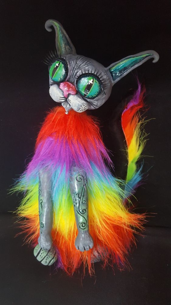 Rainbow coloured cat plush in front of a black background.