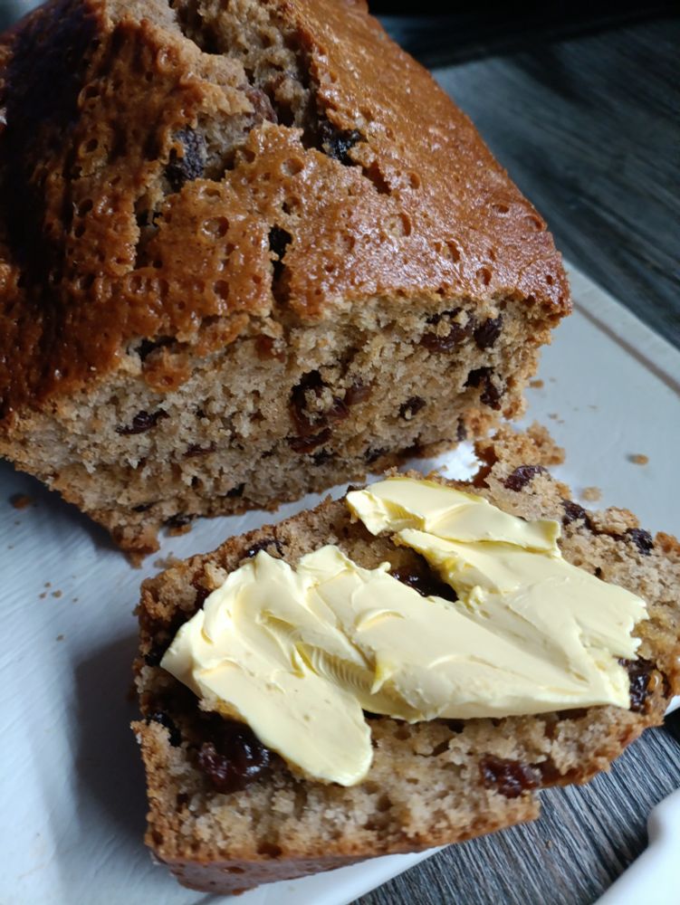 Freshly baked tea loaf, with a slice cut and butter melting on it