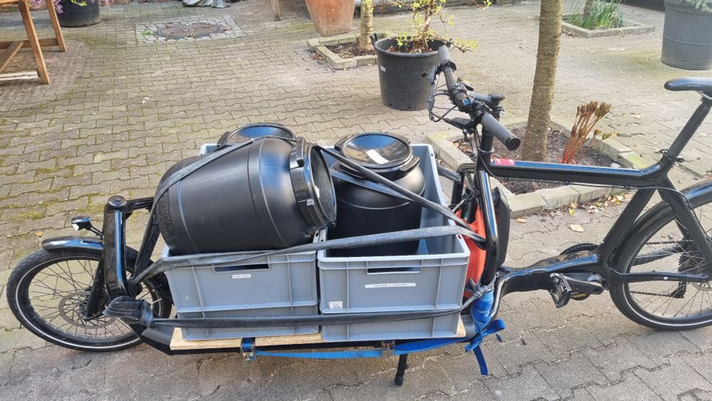 eBullitt mit 2 Euroboxen, darin 3 10kg Kaffeetonnen, eine unglücklich oben schräg drauf verzurrt.