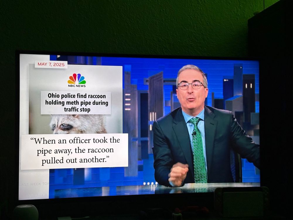 Late night host John Oliver in front of the headline “Ohio police find raccoon holding meth pipe during traffic stop: when officer took pipe away, the raccoon pulled out another” 