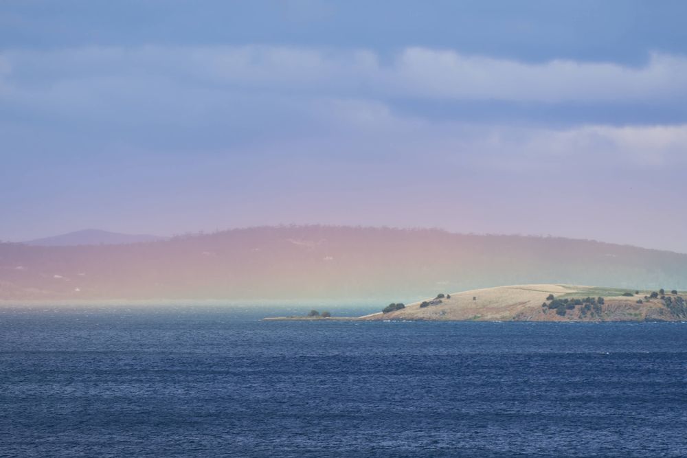 A rainbow peak at sea level covering a headland