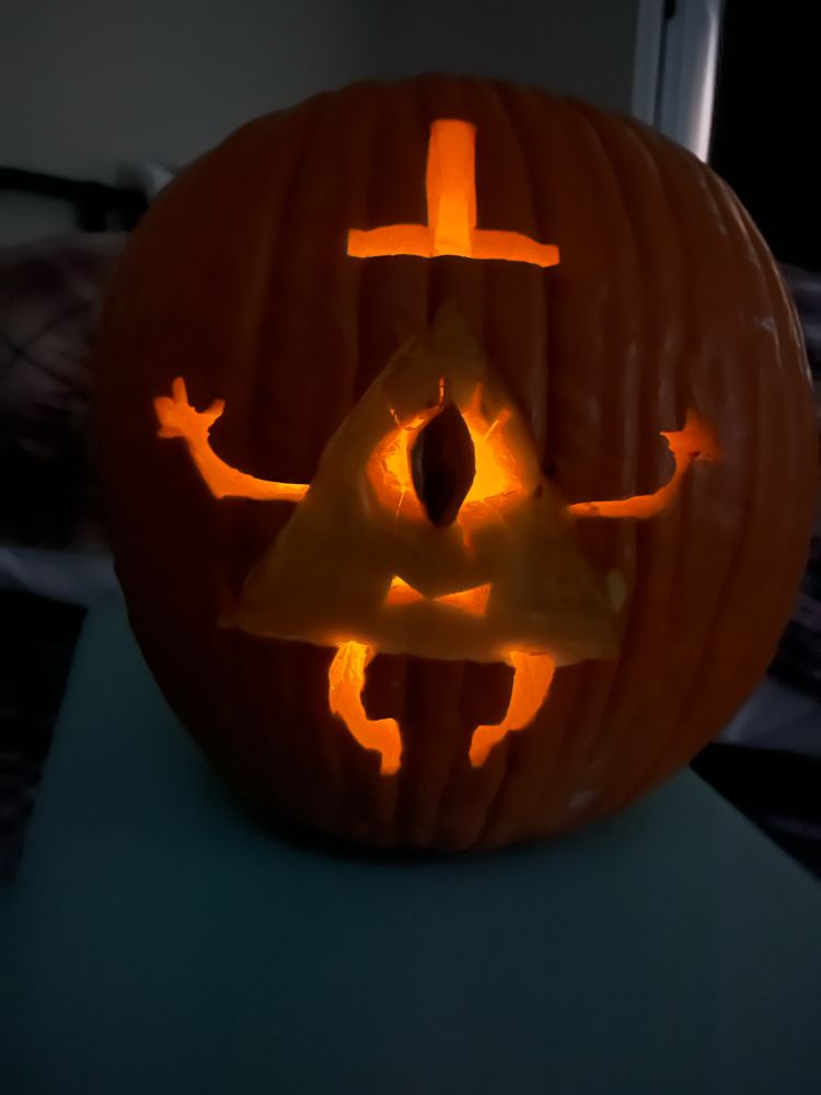 A pumpkin carving of the Gravity Falls character Bill Cipher, a triangle with one eye, a top hat, and a bow tie 