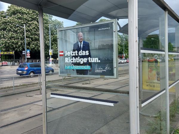 Straßenbahn-Wartehäuschen mit Werbeplakat an der Seite. Darauf ist der österreichische Bundeskanzler zu sehen, der Text sagt: "Jetzt das Richtige tun. Für Österreich."