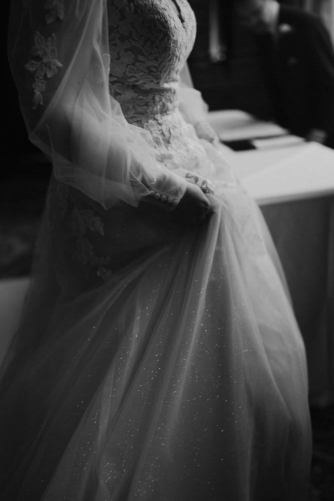 Black and white image of my wedding dress, which had a fitted bodice with lace detailing, full tuile sleeves ending in cuffs tied with small white buttons, and a full a-line tuile skirt with a layer of glitter tuile