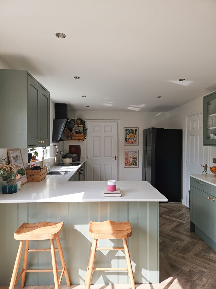newly renovated kitchen with green cabinets, carrara quarts countertops, herringbone flooring, and minimalist decor.