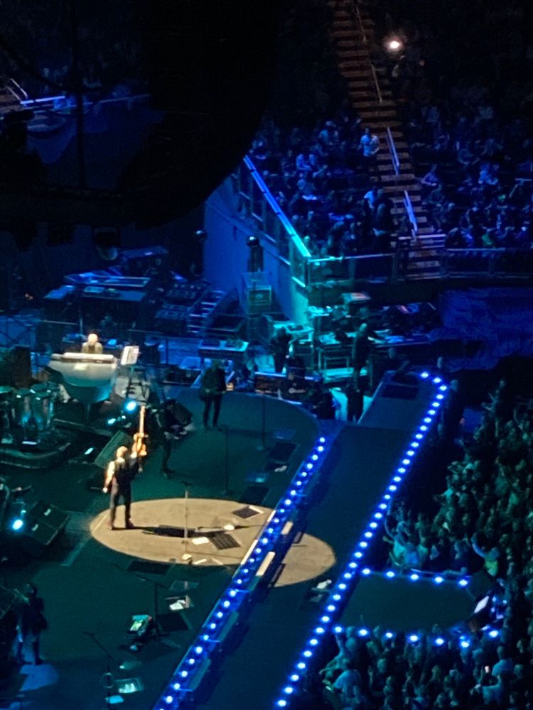 Bruce Springsteen holds up a guitar in a spotlight on a stage.