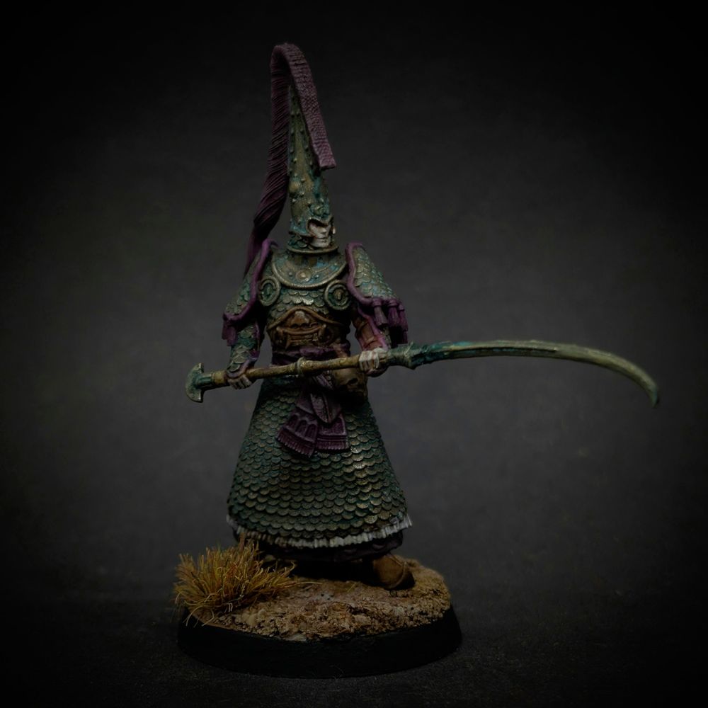 A miniature of an elf in verdigrised bronze scale armour, carrying a bronze rhomphaia.