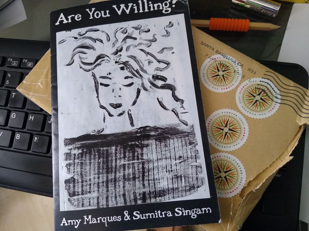 A photo of the chapbook Are You Willing by Amy Marques and Sumitra Singham with an envelope showing American postage stamps.