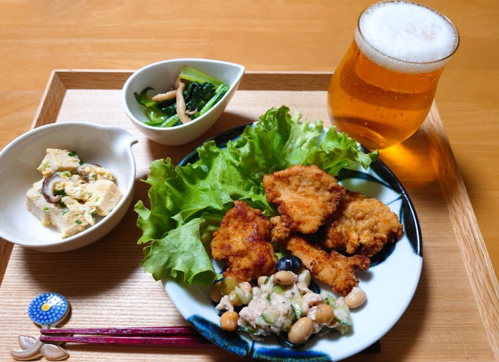 トレイに載ったビールと料理（鶏むね柚子胡椒唐揚げ・豆ときゅうりのサラダ・高野豆腐卵とじ・小松菜オイスター炒め）