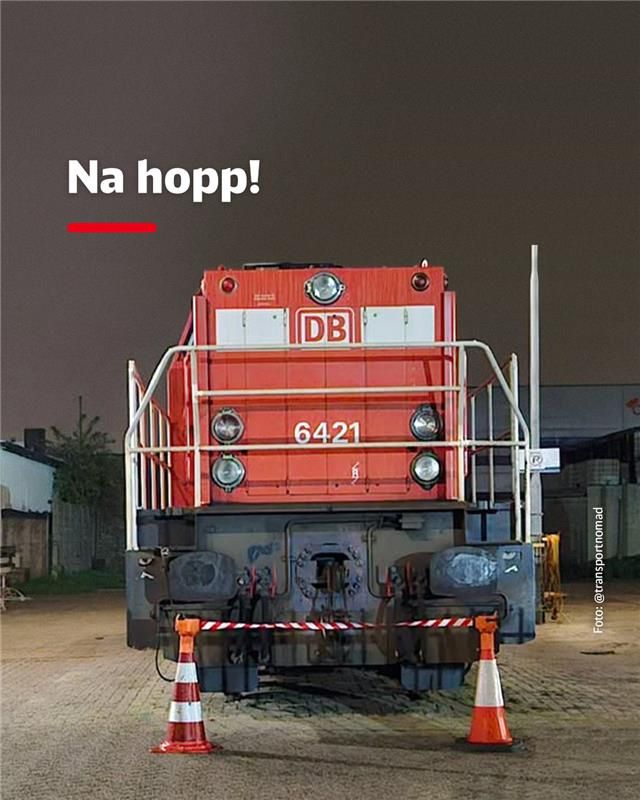 Eine Rangierlok steht vor zwei kleinen Hütchen, zwischen denen ein rot-weißes Flatterband gespannt ist. Dazu der Text: Na hopp!