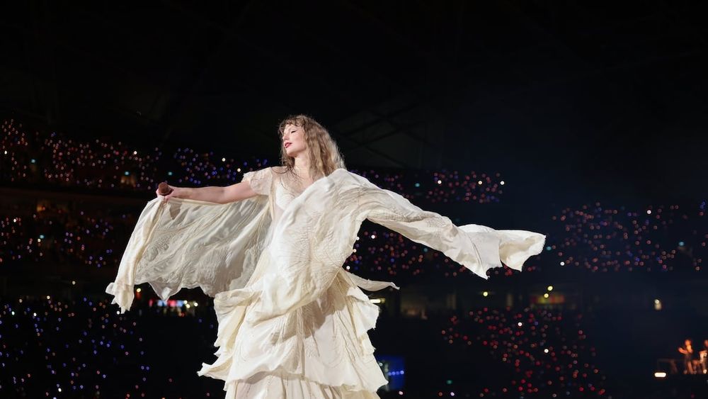 Taylor Swift twirling in a white dress with billowing sleeves to "august" at the Eras Tour