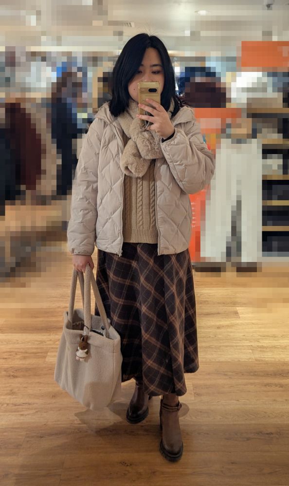 Mirror selfie of an East Asian girl wearing a deep brown checkered long skirt, a beige duffel coat, vest, scarf and holding a beige tote bag.