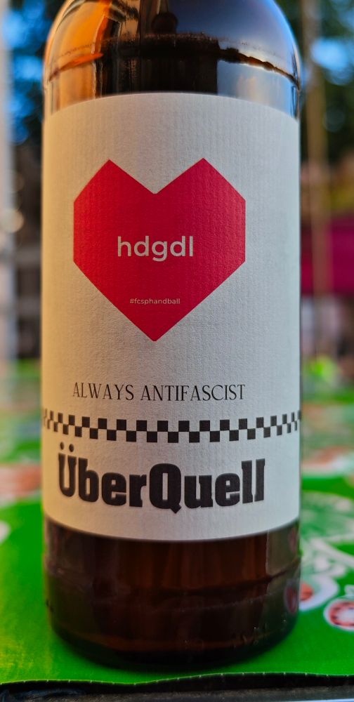 Bierflasche "Helles" mit Etikett von Brauerei Überquell. Aufdruck: stikisiertes Hert, hdgdl, #fcsphandball, Always Antifascist, Überquell