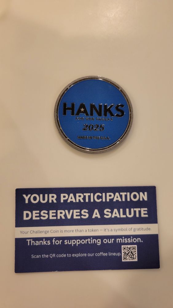 A coin with the word HANKS on it and a card with a QR Code to a coffee website