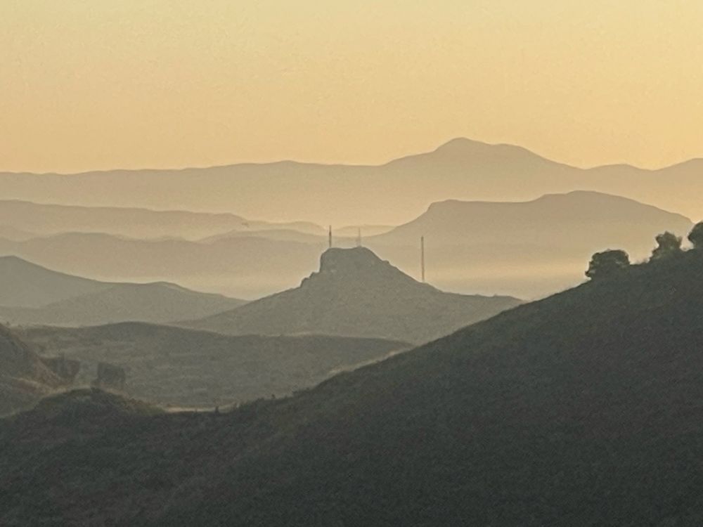 Distant hills in varying shades of sepia as the sun rises each one is a darker shade moving towards the foreground 