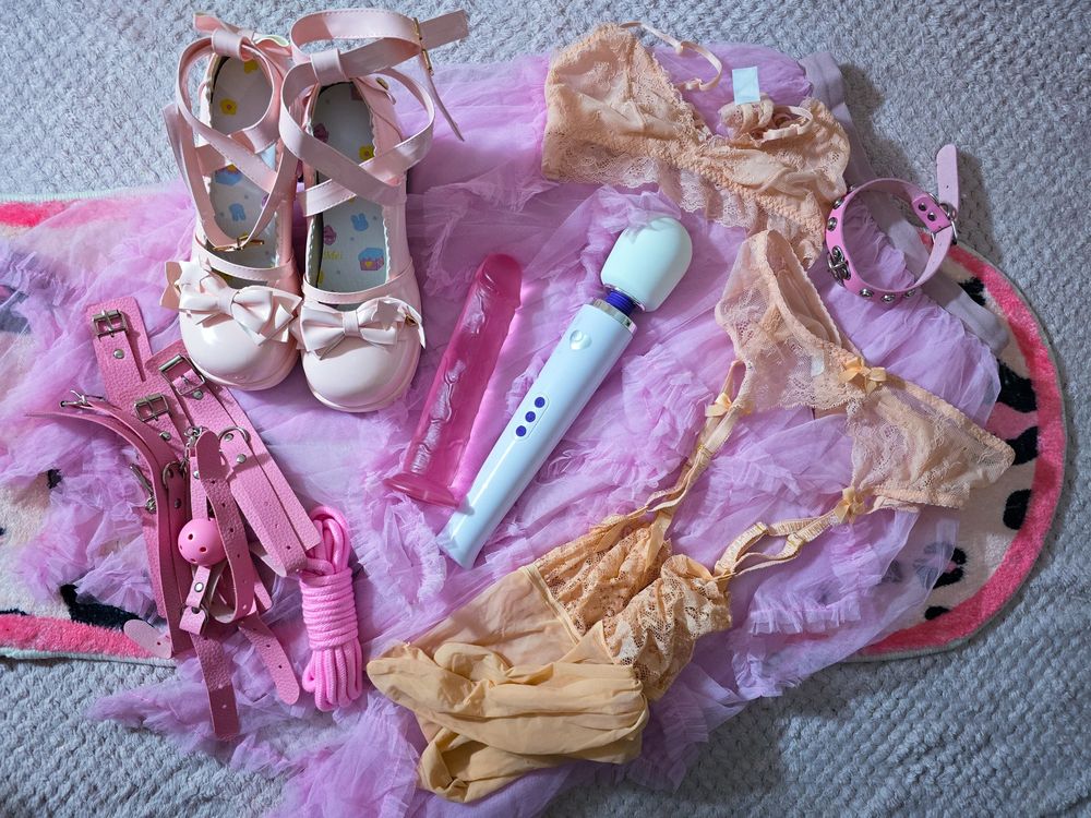 Photo of clothes and tools Ursula will wear and use today. 

Pink fairy skirt
Peach toned soft underwear and stockings set
Pale pink dolly shoes
Pink leather restraints 
Pink dildo
White wand
Pink shibari rope
Pink collar with studs 