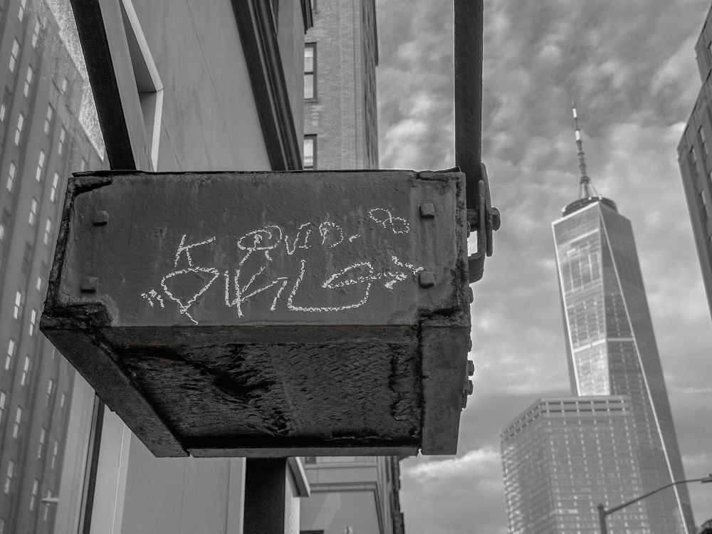 The end of a fire escape with some graffiti. In the background is the world trade tower 