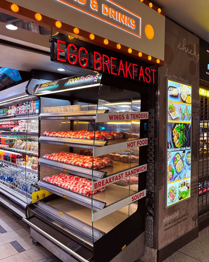 EGG BREAKFAST in neon over a heat lamp display of breakfast sandwiches 